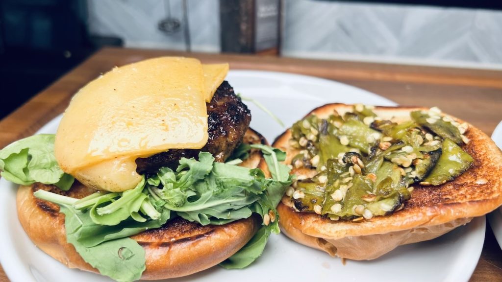 Green Chile Burgers on a toasted bun with cheese and arugula