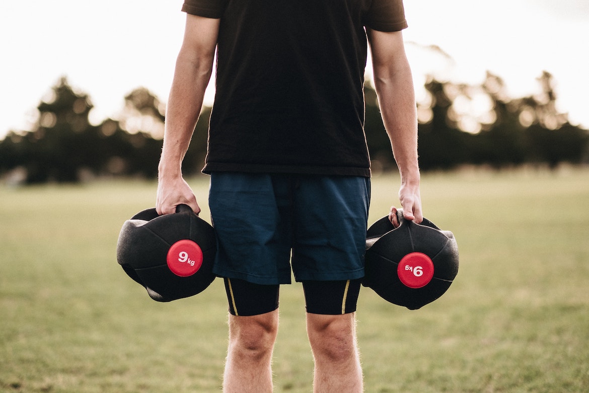 Man holding Kettle Bells in Park